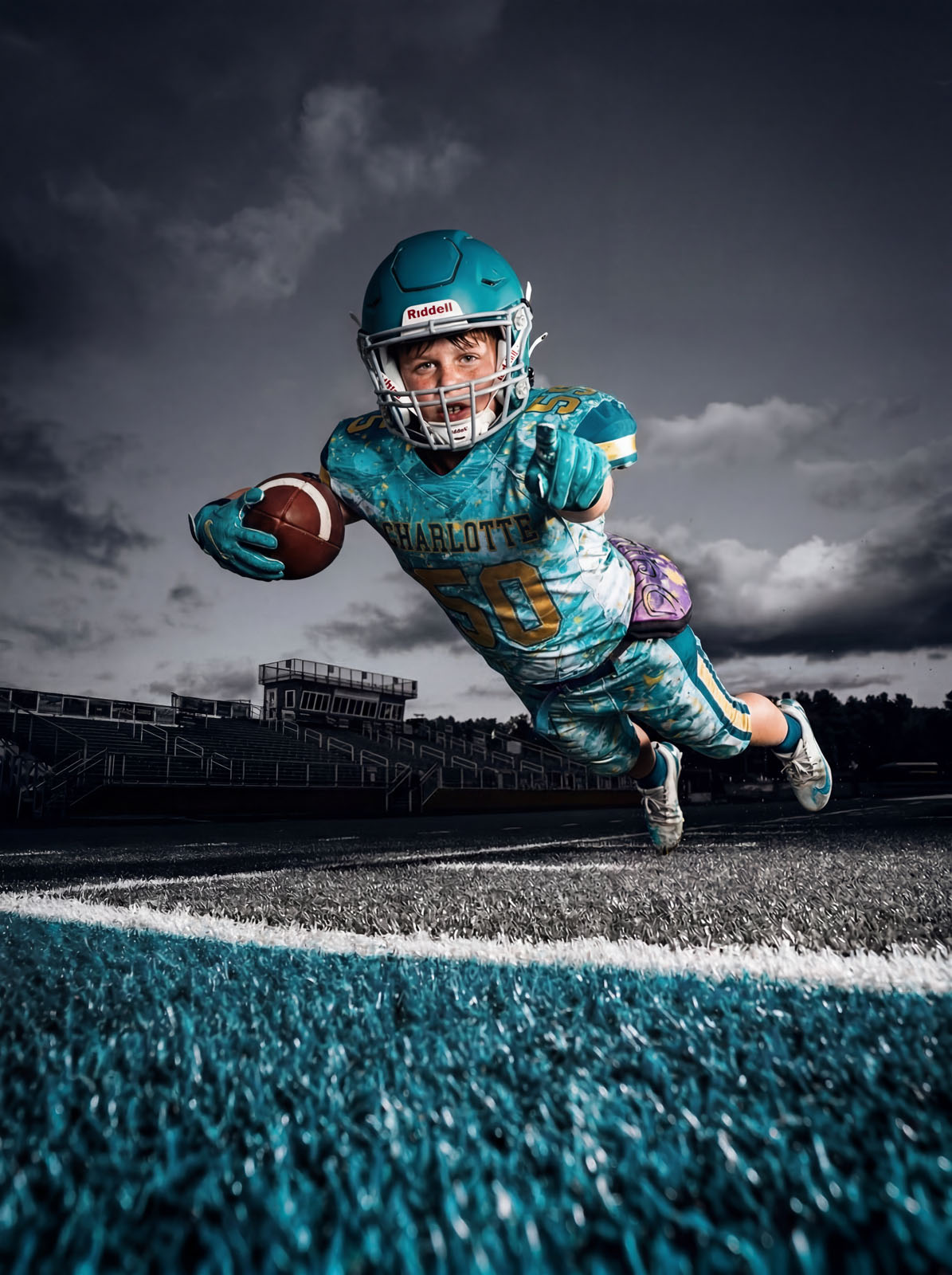 Young football player diving for a touchdown in a teal Charlotte uniform