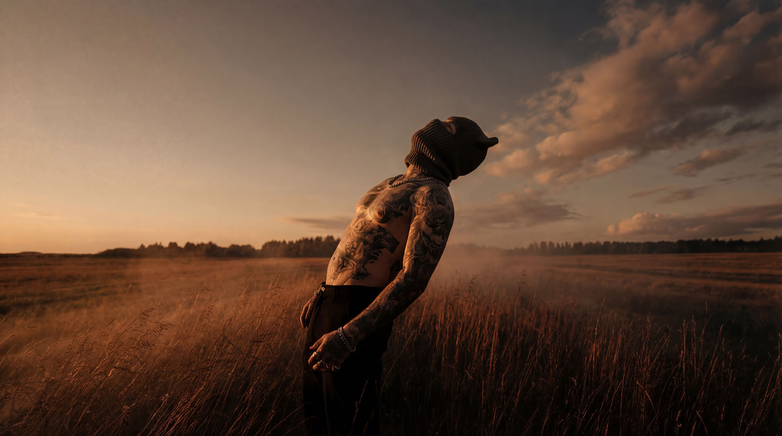 Tattooed figure in a golden field at sunset